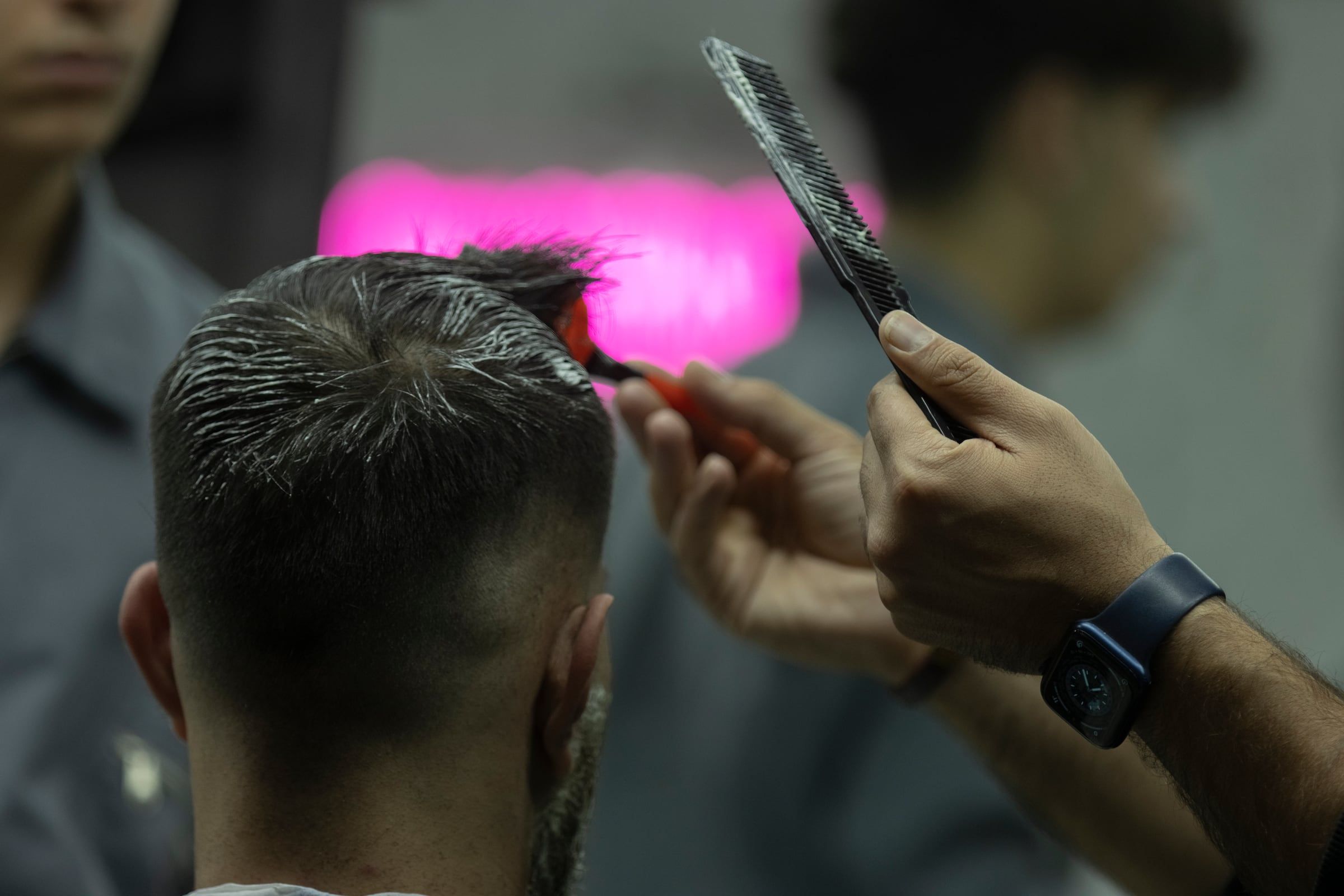 Barbero peinando la nuca de un cliente con degradado bajo